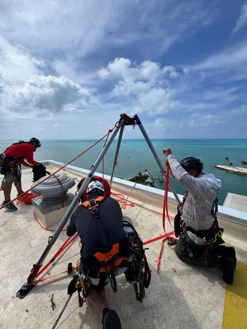 Rope-access workers setting up tripod on rooftop